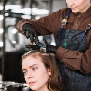 A hairstylist expertly dyes a woman's hair in a contemporary salon setting, highlighting beauty and care.